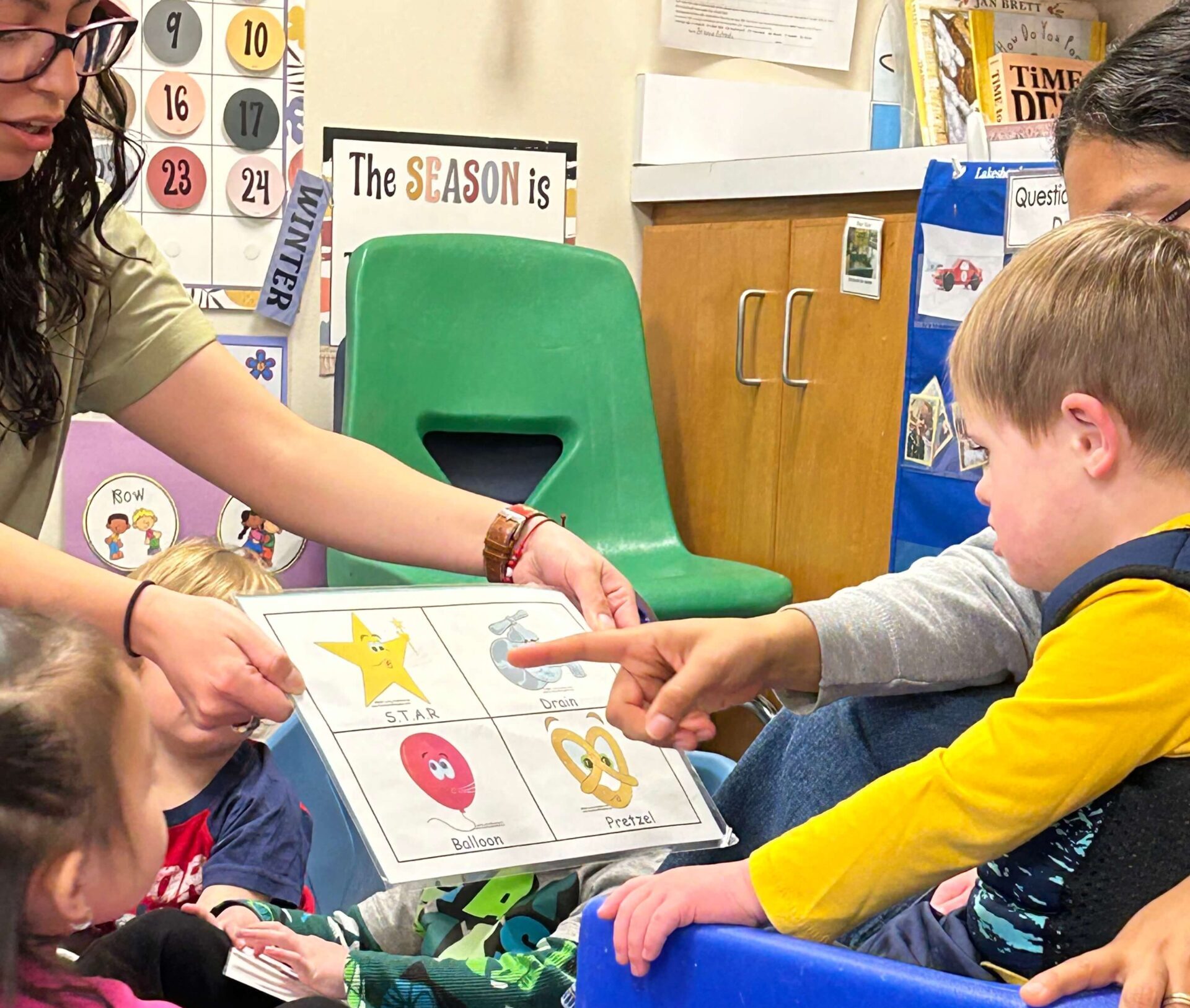 A teacher shows children a chart of Conscious Discipline breathing strategies as one child points to it.